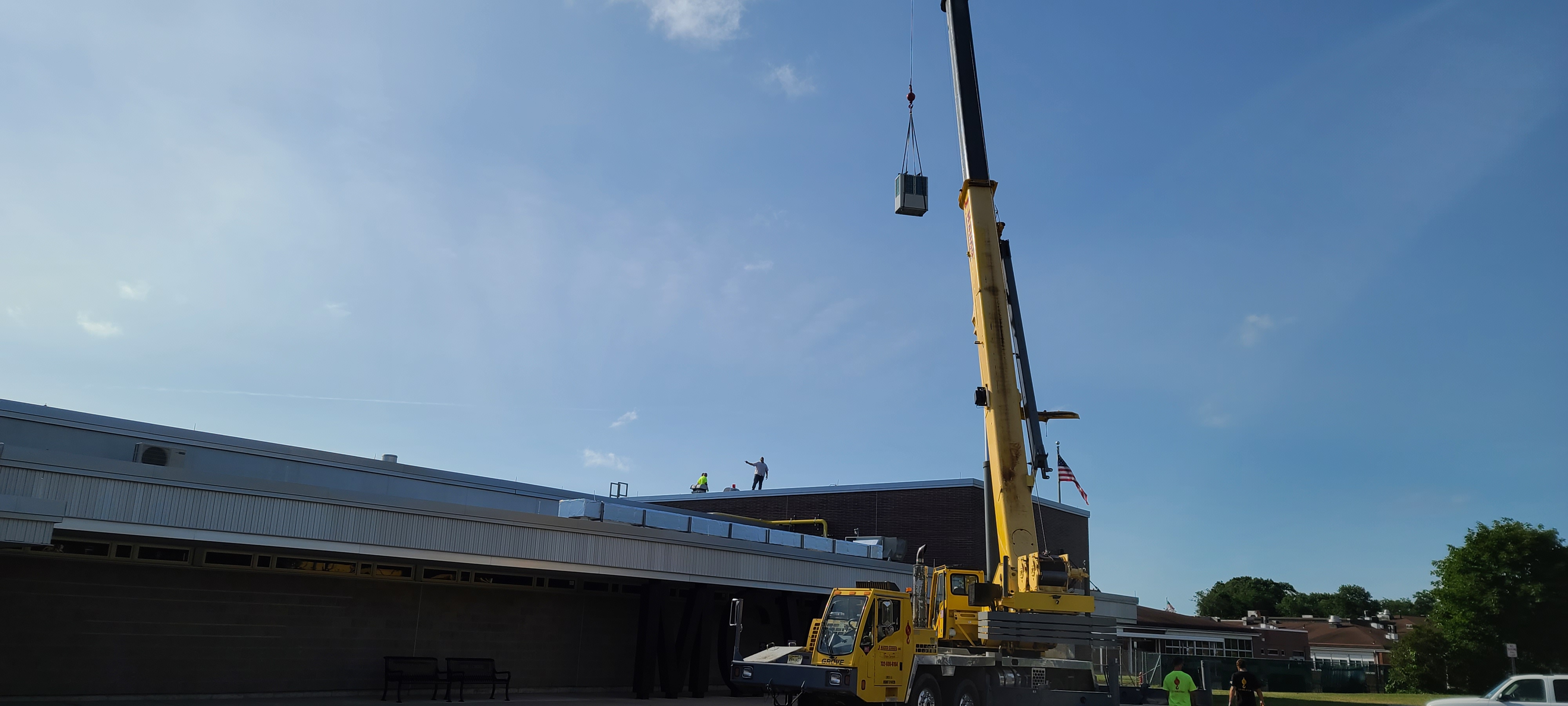 Crane lifting equipment onto a building roof